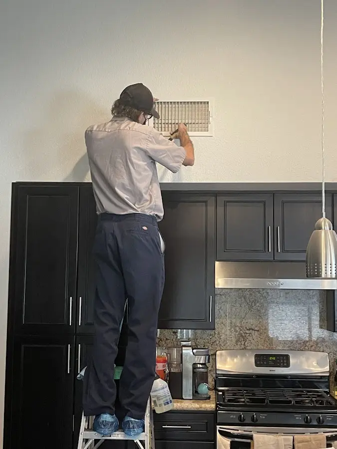 Technician inspecting an air vent during HVAC service in Jamestown